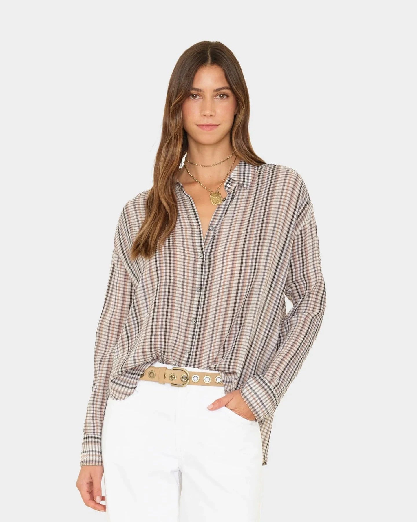 Woman wearing a plaid shirt and white pants on a white background