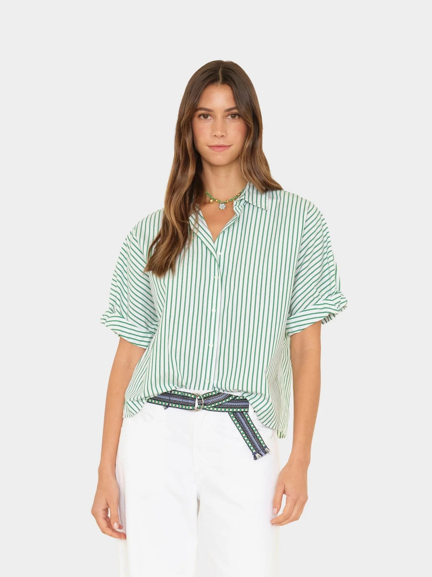 Woman wearing a green and white striped shirt with a belt on a white background