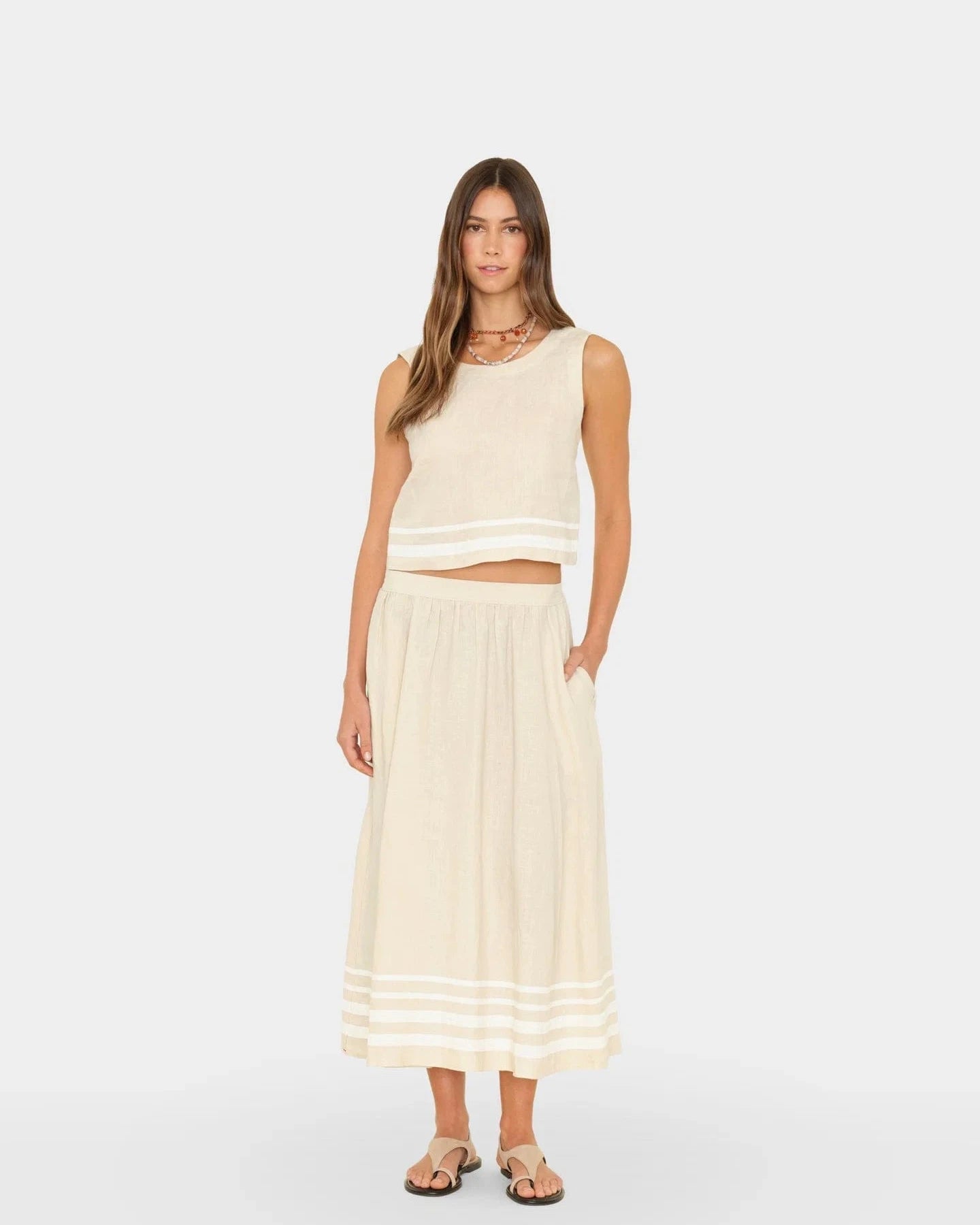 Woman wearing a cream-colored sleeveless top and skirt on a white background
