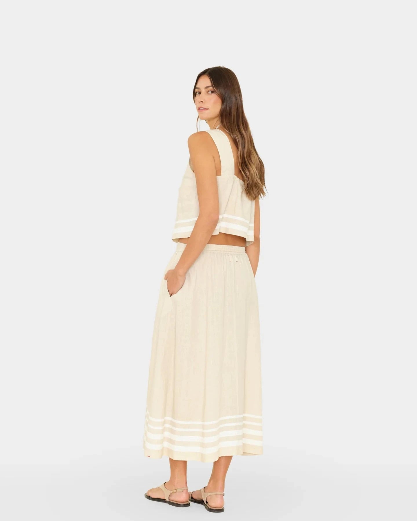 Woman wearing a white sleeveless top and skirt set on a light gray background