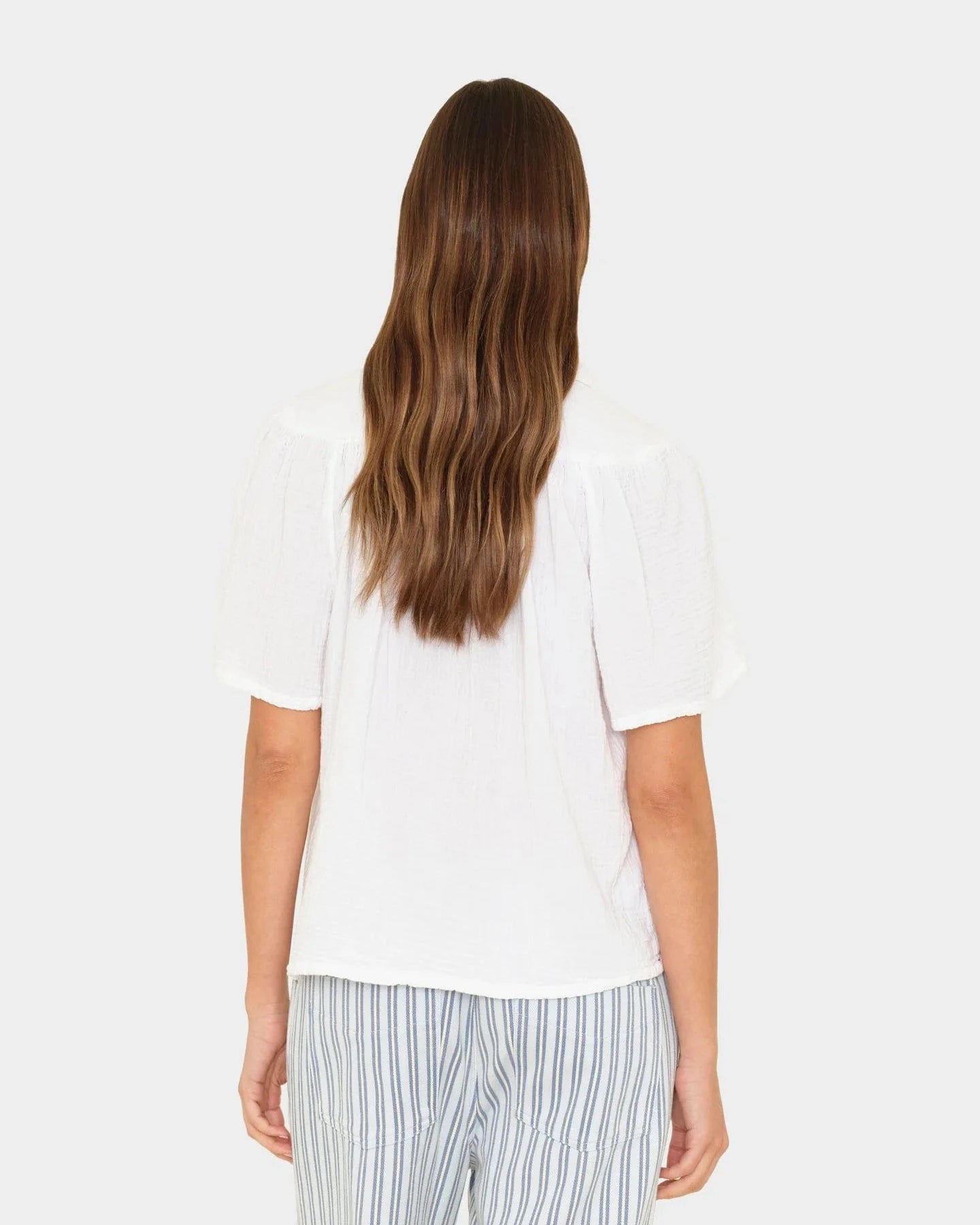 Person wearing a white top and striped pants on a white background