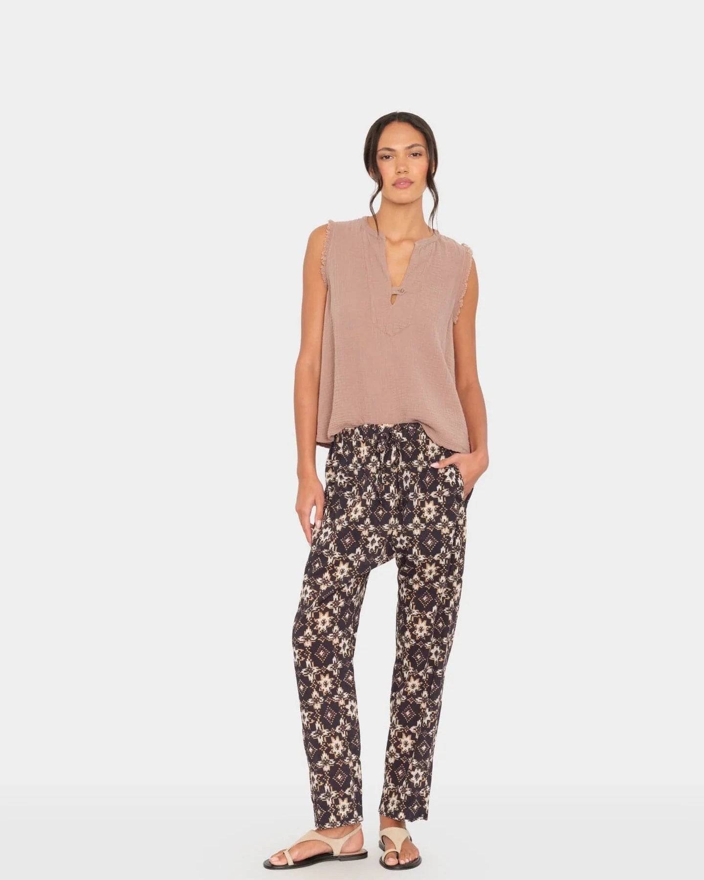 Woman wearing a sleeveless top and floral pants on a white background