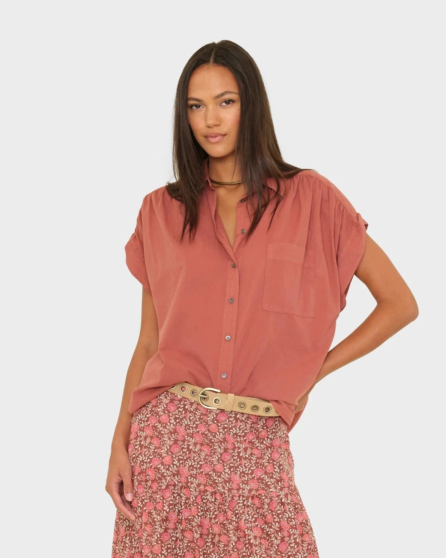 Woman wearing a pink blouse and floral skirt on a white background
