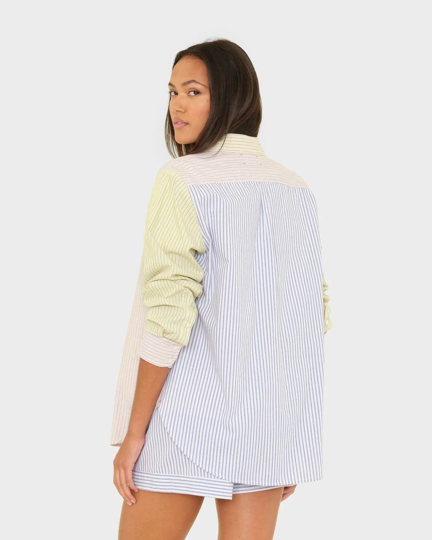 Woman wearing a colorful outfit with a striped shirt and light green sweater on a white background