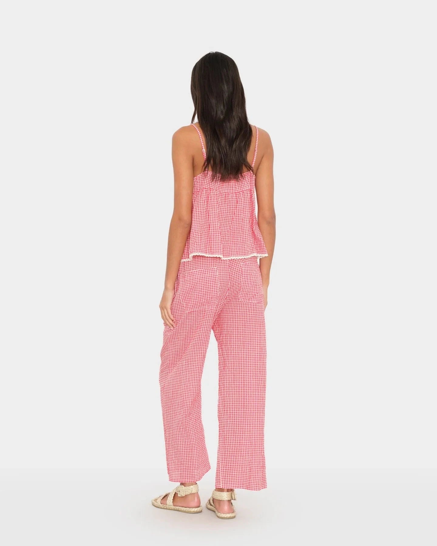 Woman wearing a pink checkered outfit on a white background