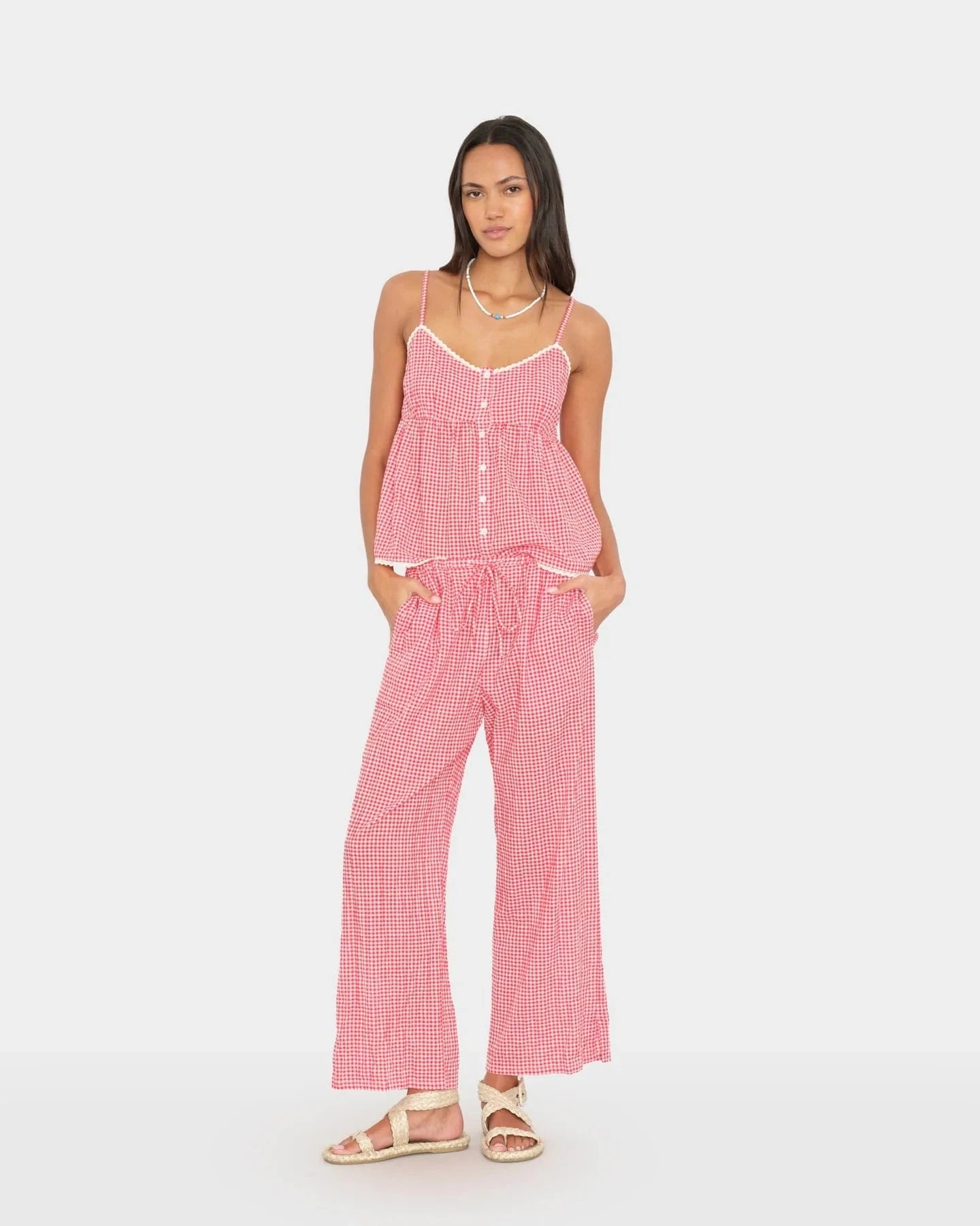 Woman wearing a pink checkered jumpsuit on a white background