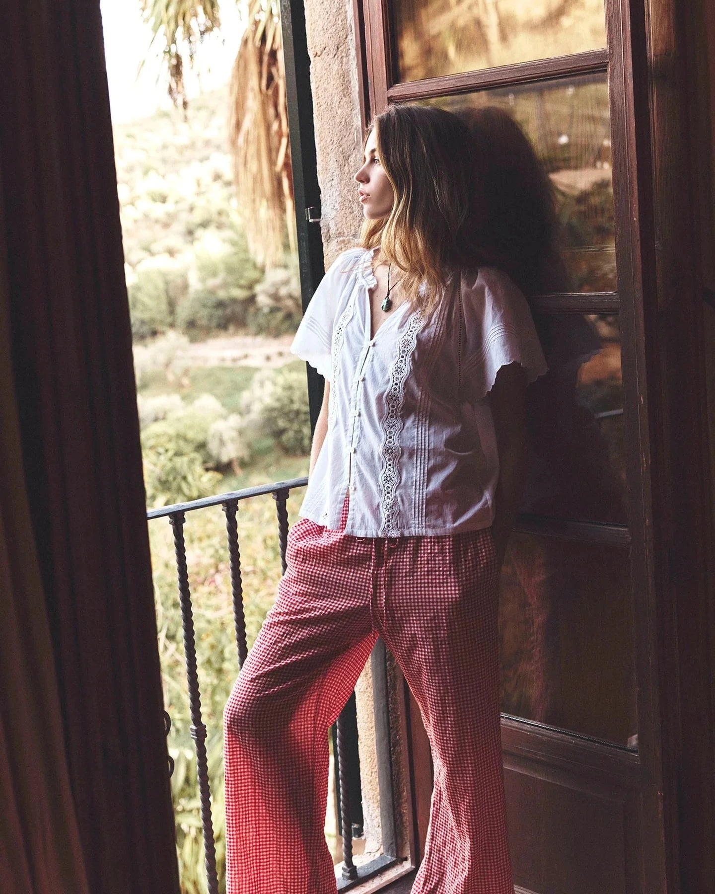 Woman standing by a window with a view of greenery