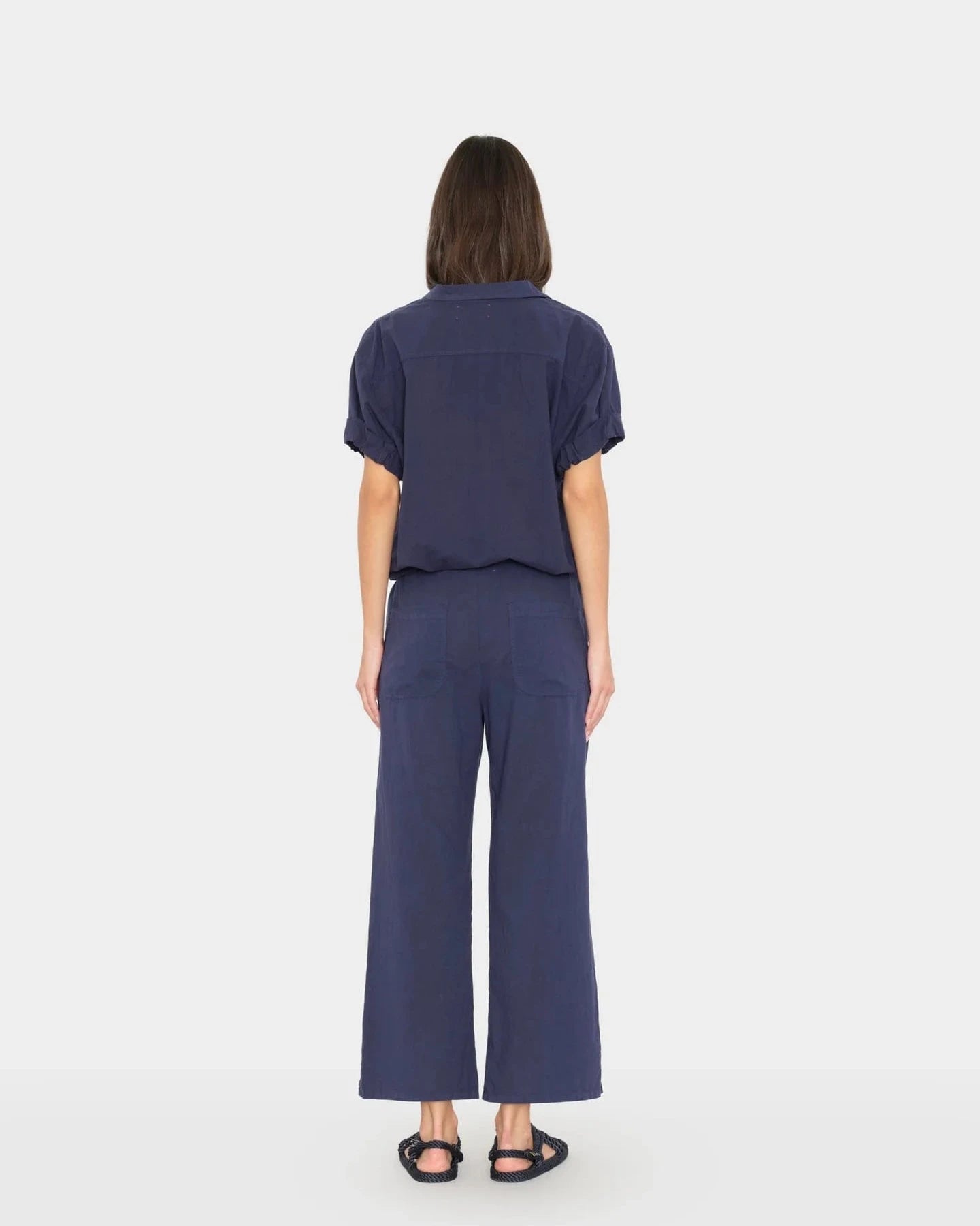 Woman wearing a navy blue outfit with wide-leg pants on a white background