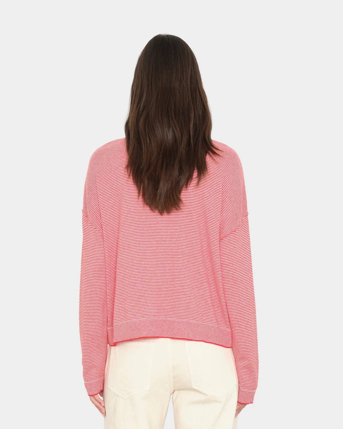 Person wearing a pink sweater on a light gray background