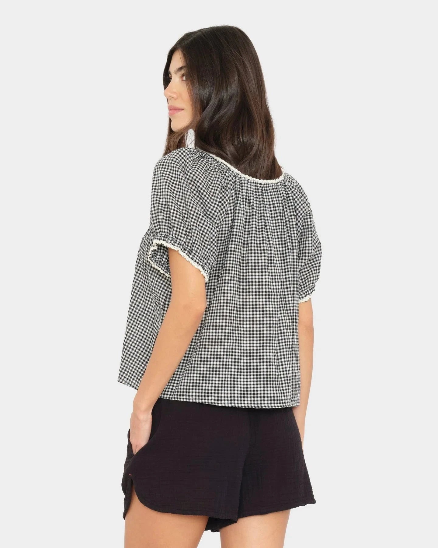 Woman wearing a black and white checkered blouse with a plain background