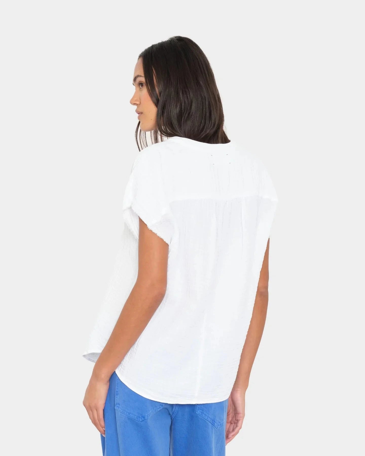 Woman wearing a white t-shirt and blue pants on a plain background