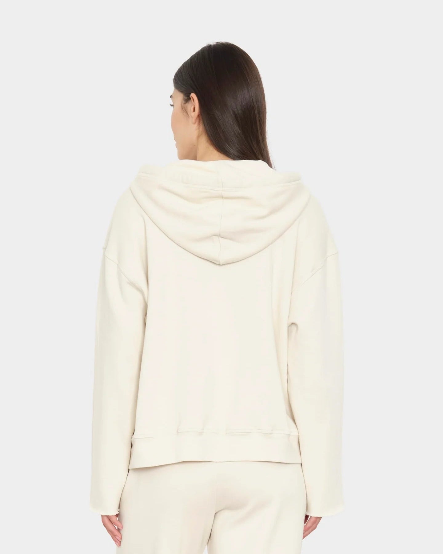 Person wearing a cream-colored hoodie and pants on a white background