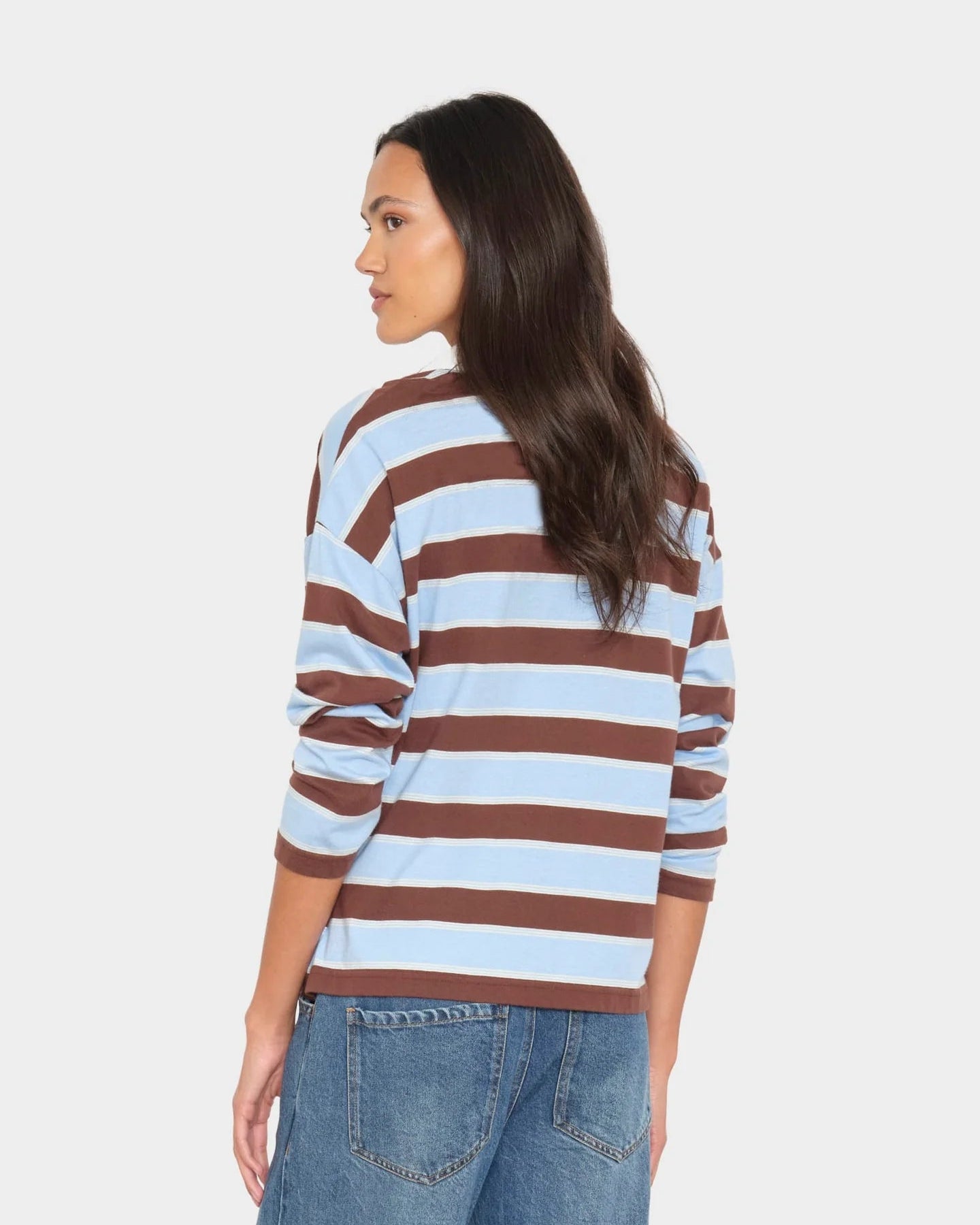 Woman wearing a striped shirt and jeans on a plain background