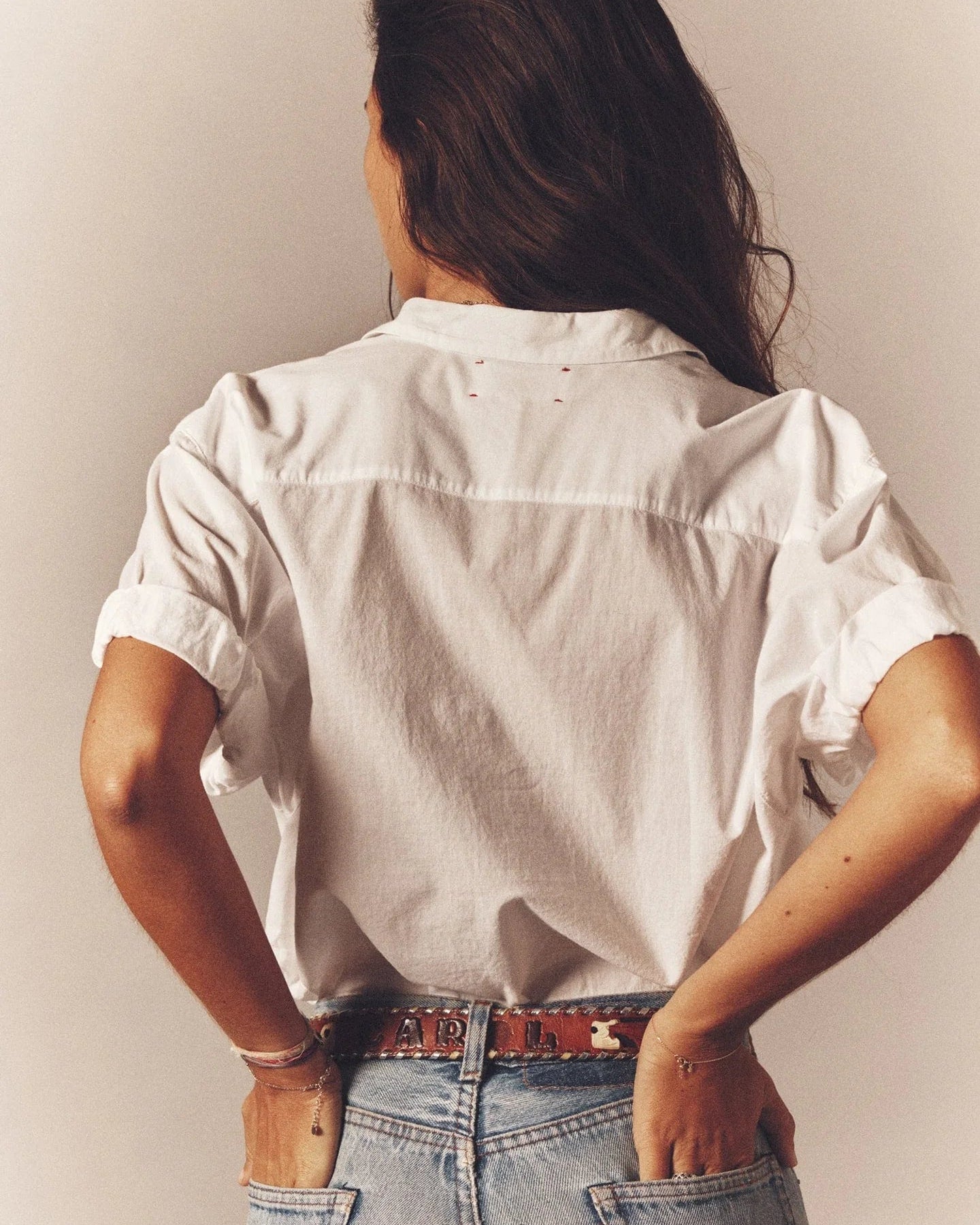 Person wearing a white shirt and blue jeans with a neutral background
